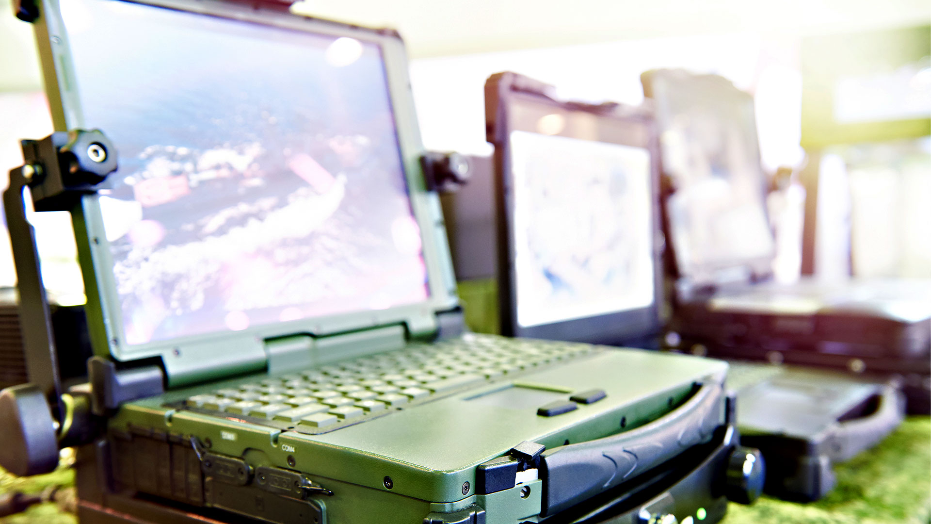 Aufgeklapptes militärisches Laptop. Auf dem BIldschirm sieht man eine Küstenbebauung